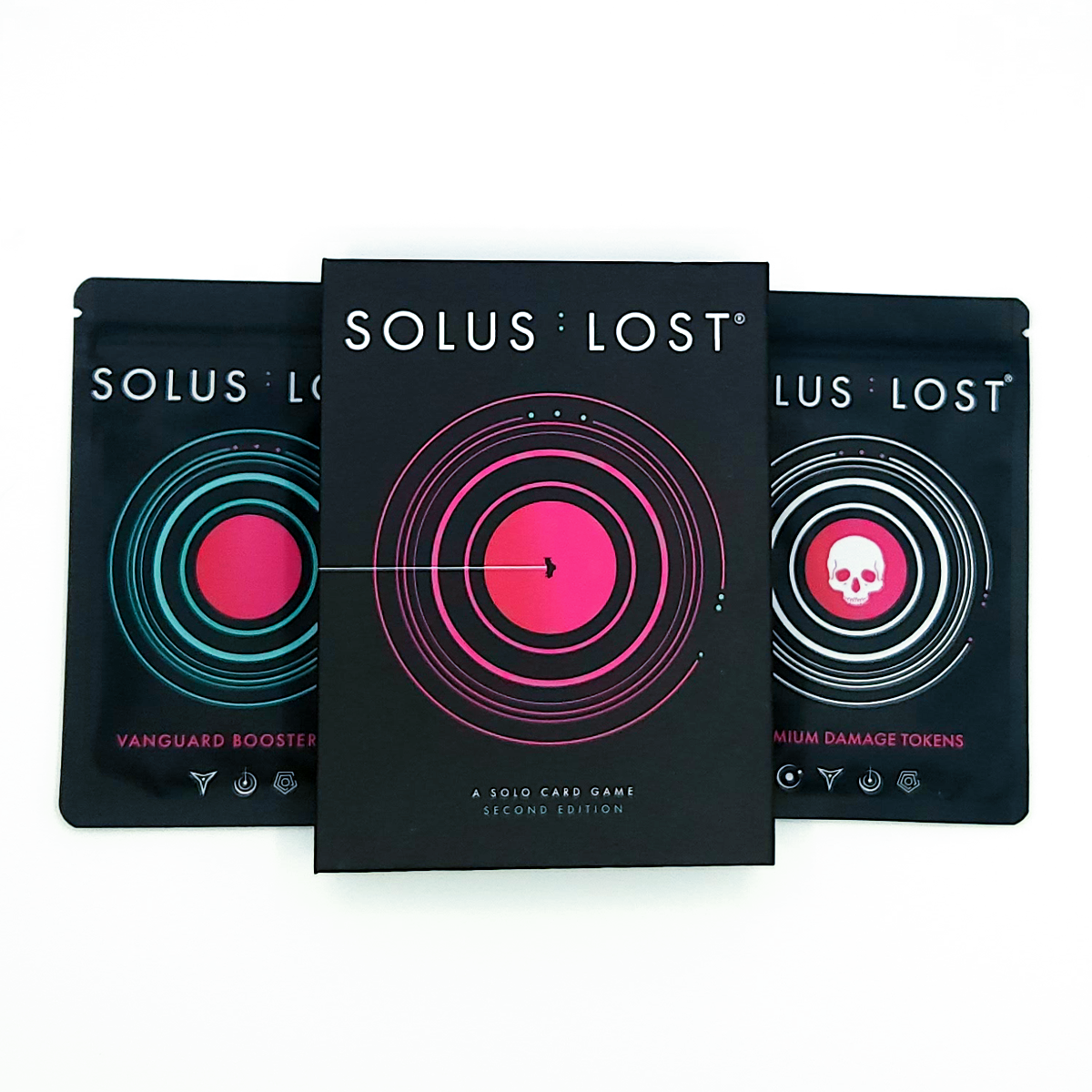 Three black Solus Lost card game booster packs arranged in a fan shape on a white background, with the center pack showing a pink circular design and the side packs showing teal and white skull designs.